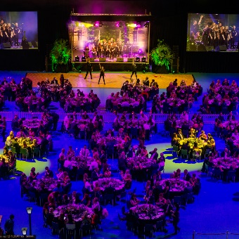 A photo of a function with tables and chairs with a stage performance at RAC Arena in Perth