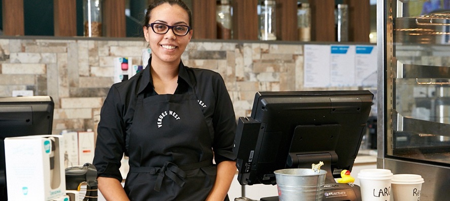 A photo of a woman standing at the counter of a cafe